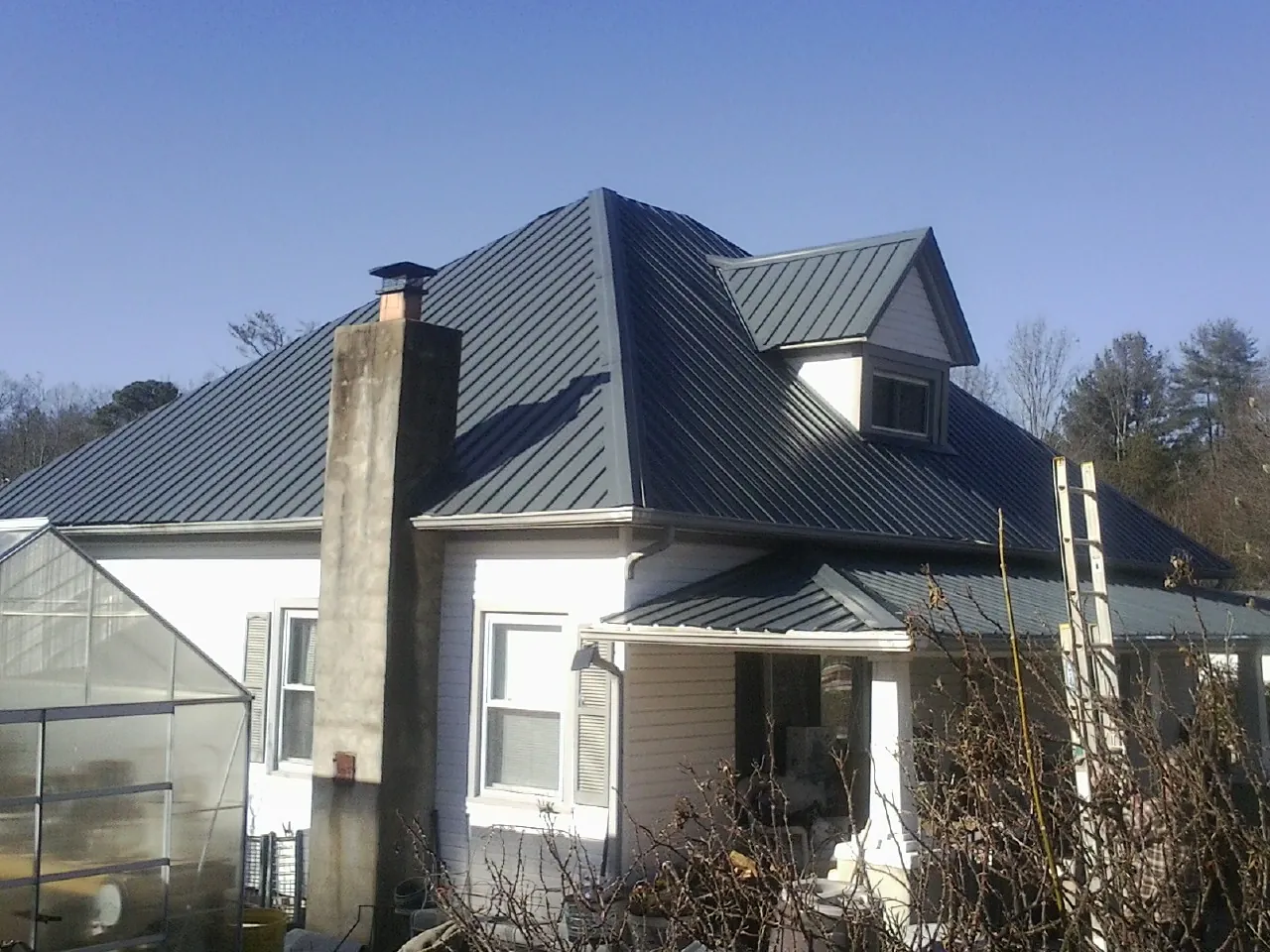 Dark blue standing seam metal roof on a white farmhouse with dormer — Slate & Tile Roof Repair by Roofing Brothers in Hamel