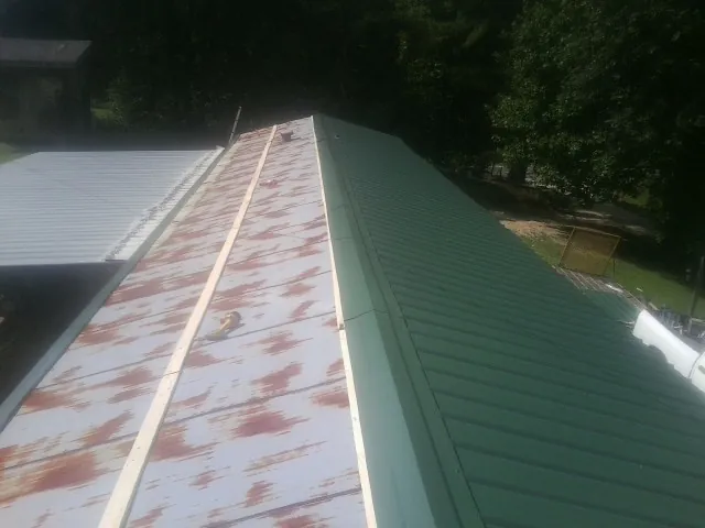 Old rusted panels beside newly installed green metal roofing — Wind Damage Roof Repair by Roofing Brothers in Hamel