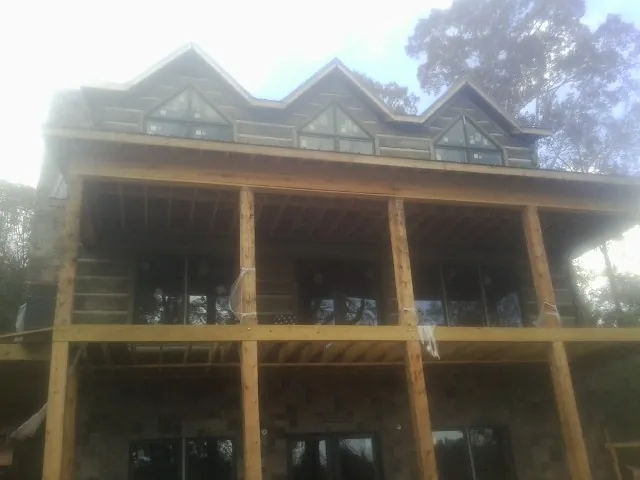 Dormers and porch framing on a large log home under construction — Roof Coating work by our crew in Hamel