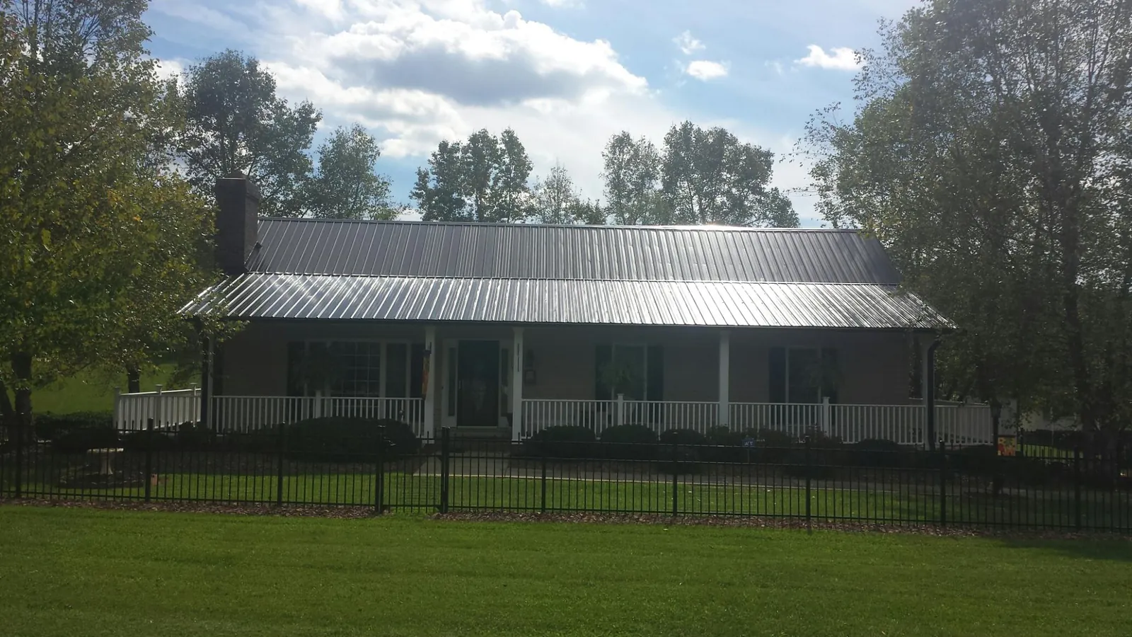 Gray metal roof on a brick ranch with a full width front porch — Gutter Guard Installation work by our crew in Hamel