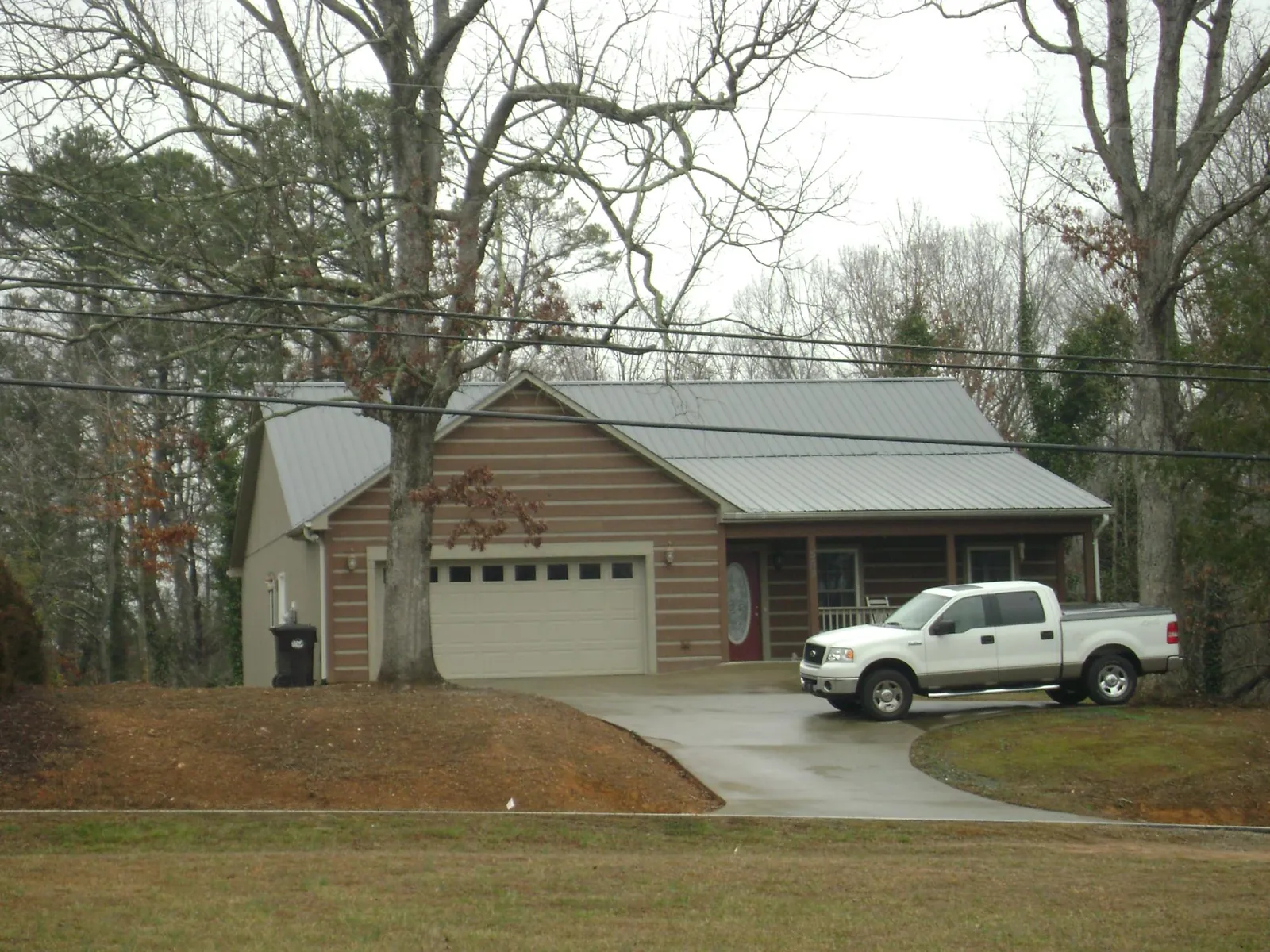 Gray metal roof on a log sided house with an attached two car garage in Hamel