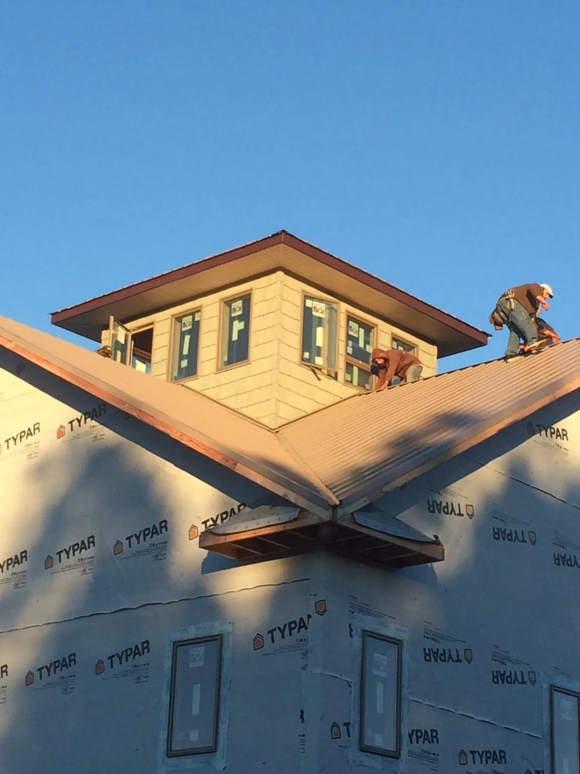 Roofers working around a rooftop cupola on a new metal roof at sunset — Roof Waterproofing in Hamel by Roofing Brothers